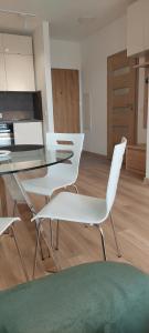 切霍齐内克nowy apartament的一间用餐室,配有白色的椅子和玻璃桌