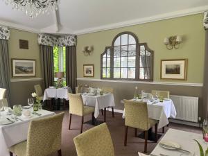 格拉斯米尔The Grasmere Hotel的一间带桌椅的用餐室和窗户。