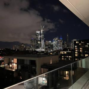 墨尔本Carlton Stunning View Apartment with Free Parking -2的建筑在晚上可欣赏到城市美景