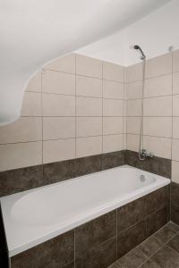 卡拉瓦杜斯Mandi's Apartments的带浴缸的浴室和瓷砖墙