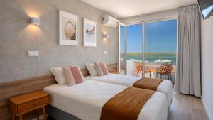 法鲁Hotel Made inn Faro的酒店客房设有两张床和大窗户。