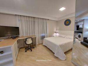 圣保罗Bienal Ibirapuera的一间卧室配有一张床和一张书桌及电视