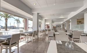 罗列特海岸Rosamar Maritim 4*的餐厅拥有白色的桌椅和棕榈树