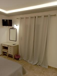 马拉希亚斯Olive house的卧室配有白色窗帘、书桌和床。