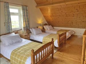 Aughrus MoreLands End Cottage - Connemara的一间卧室设有两张床和窗户。