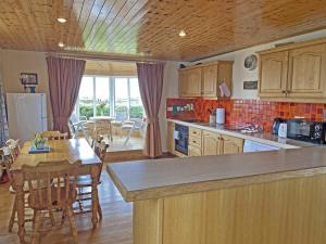 Aughrus MoreLands End Cottage - Connemara的一间带木制橱柜和桌子的厨房以及一间用餐室
