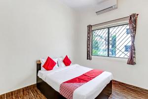 ChikalthānOYO Shree Balaji Lodging的一间卧室配有一张带红色枕头的床和一扇窗户