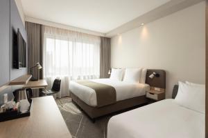 埃因霍温Holiday Inn - Eindhoven Airport, an IHG Hotel的酒店客房设有两张床和电视。