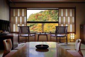 藏王温泉Zao Onsen Omiya Ryokan的客房设有桌椅和大窗户。