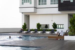 马六甲Amber Cove Impression City Melaka By Dawn Stay Free Netflix的两人在大楼的游泳池游泳