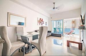 卡塔赫纳Apartamento lujoso a un minuto de la playa del laguito, la mejor playa de Cartagena de Indias的客厅配有玻璃桌和椅子