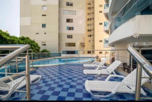 卡塔赫纳Apartamento lujoso a un minuto de la playa del laguito, la mejor playa de Cartagena de Indias的一个带椅子的阳台和一个位于大楼内的游泳池