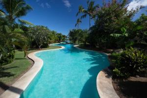 普纳奥亚Vaiava Beach Carlton- Tahiti - beachfront luxury residence & pool - 4 pers的蓝水和棕榈树度假村内的游泳池