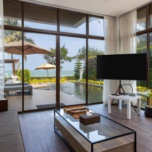 盼武里Tolani Le Bayburi Villas, Hua Hin - Pranburi的一间带电视和大窗户的客厅