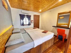 仙本那Singamata Resort的配有镜子和椅子的客房内的两张床