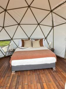 派帕Glamping Altos De Hayuelos的圆顶帐篷内的一张床位,铺有木地板