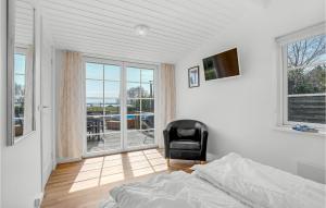 StavrebyBeautiful Home In Prst With House Sea View的一间带一张床和一把椅子的卧室以及一个阳台