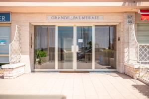 芒通La Grande Palmeraie - Spacieux studio avec vue mer, terrasse, port de Garavan的建筑物的玻璃门,上面有标志