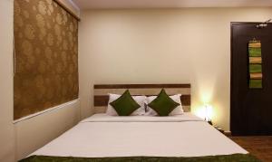 海得拉巴Treebo Trend Address Inn的卧室配有带绿色枕头的大型白色床