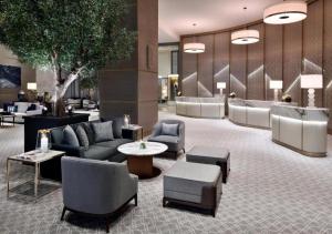 迪拜Deluxe - Address Dubai Mall - The Residence的酒店大堂设有长沙发、椅子和一棵树