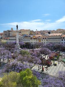 里斯本Liberator Rossio的享有紫色树木和建筑的城市美景