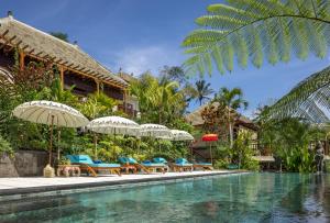 吉安雅Villa Lembah Damai by Pramana Villas的度假村的游泳池,配有椅子和遮阳伞