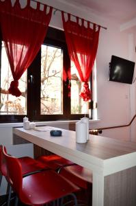 尼什Apartmants Night Lux的一间设有红色窗帘和红色椅子的书桌的房间