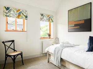 BramleyLantern Lodge的一间卧室配有一张床和一把椅子,还有两个窗户