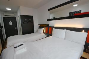 泰恩河畔纽卡斯尔纽卡斯尔便捷酒店的配有2张床铺、白色床单和遥控器的客房
