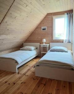 斯瓦热沃Morska Osada Swarzewo的卧室设有两张床,配有木墙和窗户。