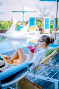 勒吉安帕德玛拉玛酒店的坐在游泳池躺椅上的女人喝一杯