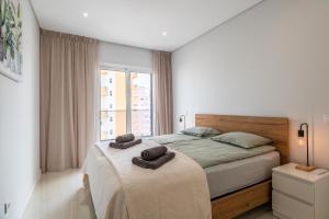 波尔蒂芒Apartamento Rocha Mar by Portucasa的一间卧室配有一张床,上面有两条毛巾