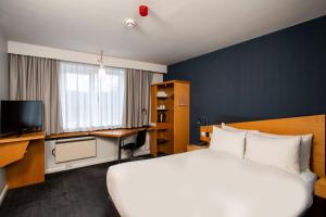 曼彻斯特快捷假日曼切斯特索尔福德码头酒店的酒店客房设有一张大床和一张书桌。