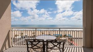 大洋城Holiday Inn & Suites Ocean City, an IHG Hotel的阳台配有桌子,享有海滩美景
