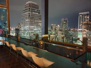 曼谷曼谷索拉利亚西铁饭店的阳台配有椅子,晚上则享有城市天际线