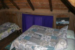 摩根湾Yellowwood Forest Eco Retreat的一间卧室配有一张床和紫色窗帘