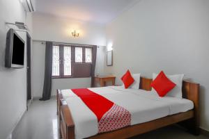 钦奈OYO Home Tree Service Apartment Near Saravana Stores T Nagar的一间卧室配有一张带红色枕头的床和一台电视。