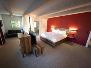因斯布鲁克伊格尔斯运动酒店的一间卧室设有一张大床和红色的墙壁