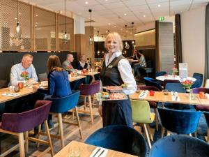 汉诺威美居汉诺威城市酒店的站在餐馆里吃一盘食物的女人