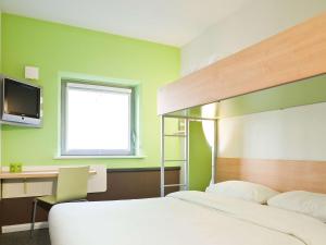 亚琛亚琛北宜必思快捷酒店的一间卧室配有一张床、一张书桌和一台电视