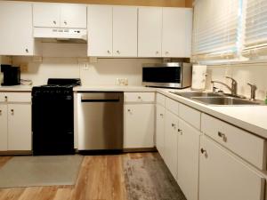 莱克兰EXQUISITE FAMILY HOME的厨房配有白色橱柜、水槽和洗碗机。