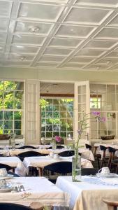 古兹耶姆JANTZENs HOTEL的一间设有白色桌椅和窗户的用餐室