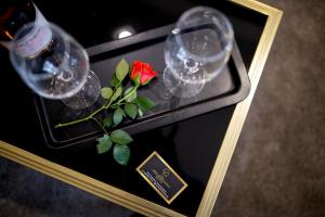 桑丹斯基Hotel CITY Sandanski的酒杯桌子和红玫瑰