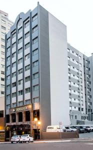 隆德里纳波旁隆德里纳商务酒店的一座大型建筑,前面有汽车停放