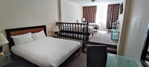 曼彻斯特曼彻斯特市中心大不列颠酒店的一间卧室配有两张床和一张婴儿床。