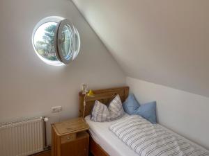 诺尔多夫Nolte Faarderhuuch 7的一间小卧室,配有一张带圆形窗户的床