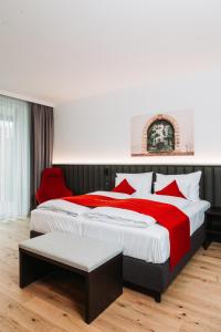 Hotel Das Grambacher的一间卧室配有一张大床和一张红色椅子