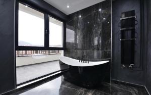 弗尔尼亚奇卡矿泉镇Spa Resort & Hotel Vrnjačke Terme的黑色浴室设有白色浴缸和窗户。
