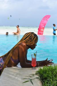 帕杰NDAME Paje Hotel的躺在海滩上喝一杯的比基尼女人