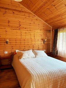 Leskovik法尔马索提拉农家乐的木制客房内的一间卧室,配有一张床
